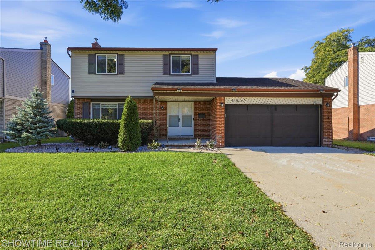 Two-story suburban house with a brick-and-siding exterior, double garage, and broad front lawn.