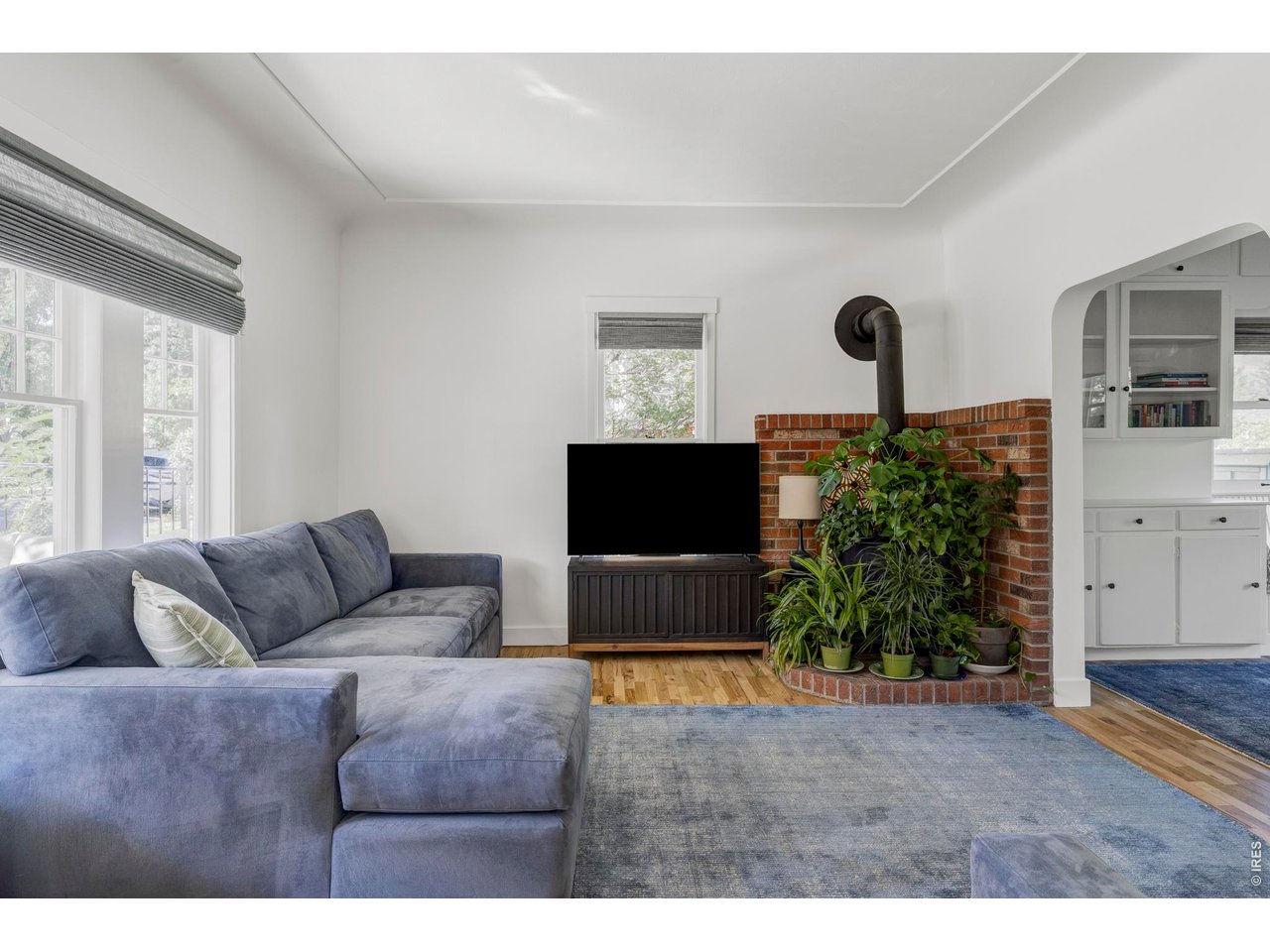 Living room with a blue sectional, brick fireplace, and wood-burning stove.