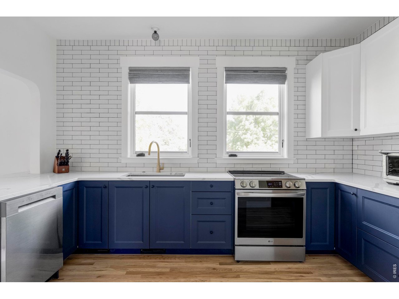 Kitchen with navy cabinets, white tile walls, and stainless steel appliances.