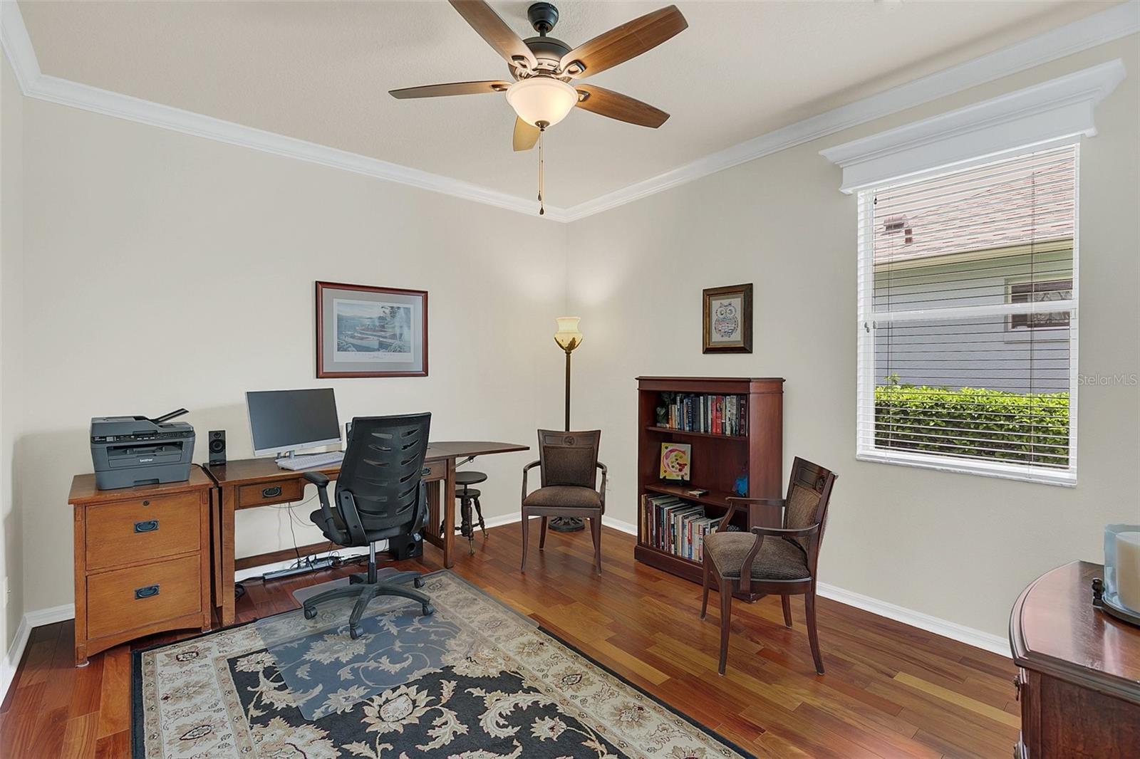 Home office with a wooden desk and computer, bookcase, and hardwood floors.