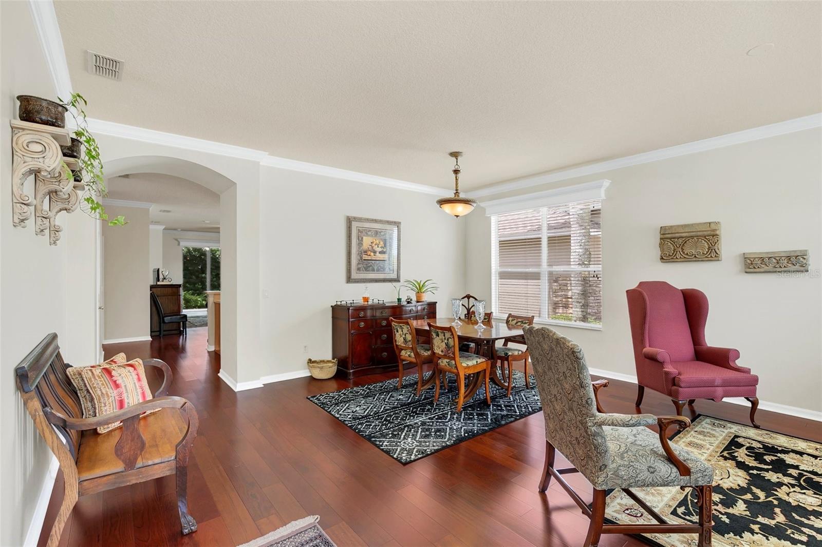Dining room with hardwood floors, a patterned rug, wooden dining set, and upholstered chairs.