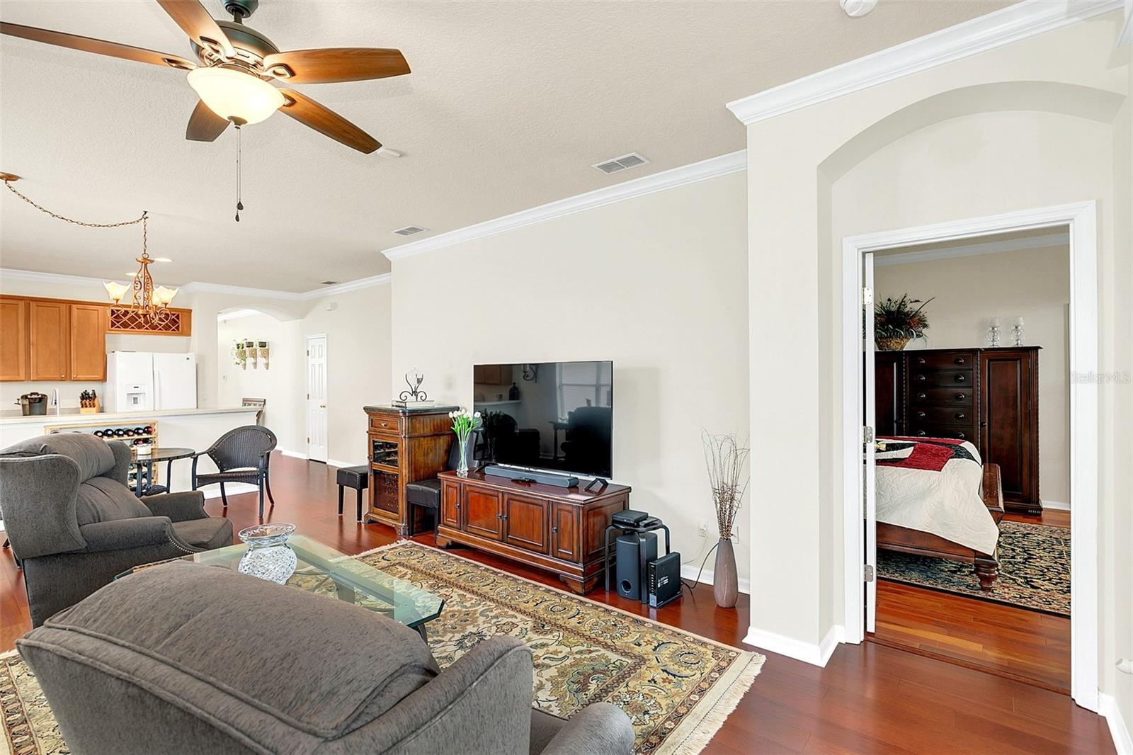 Open living room with gray sectional, patterned rug, and view into the kitchen and bedroom.