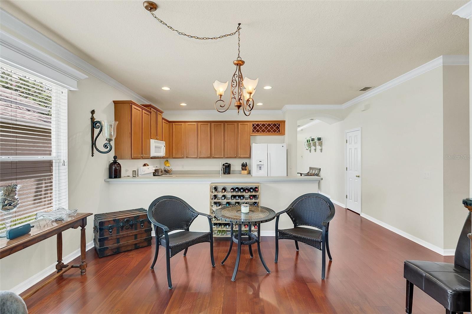 Kitchen and dining area with wood cabinetry, breakfast bar, wine rack, and hardwood floors.