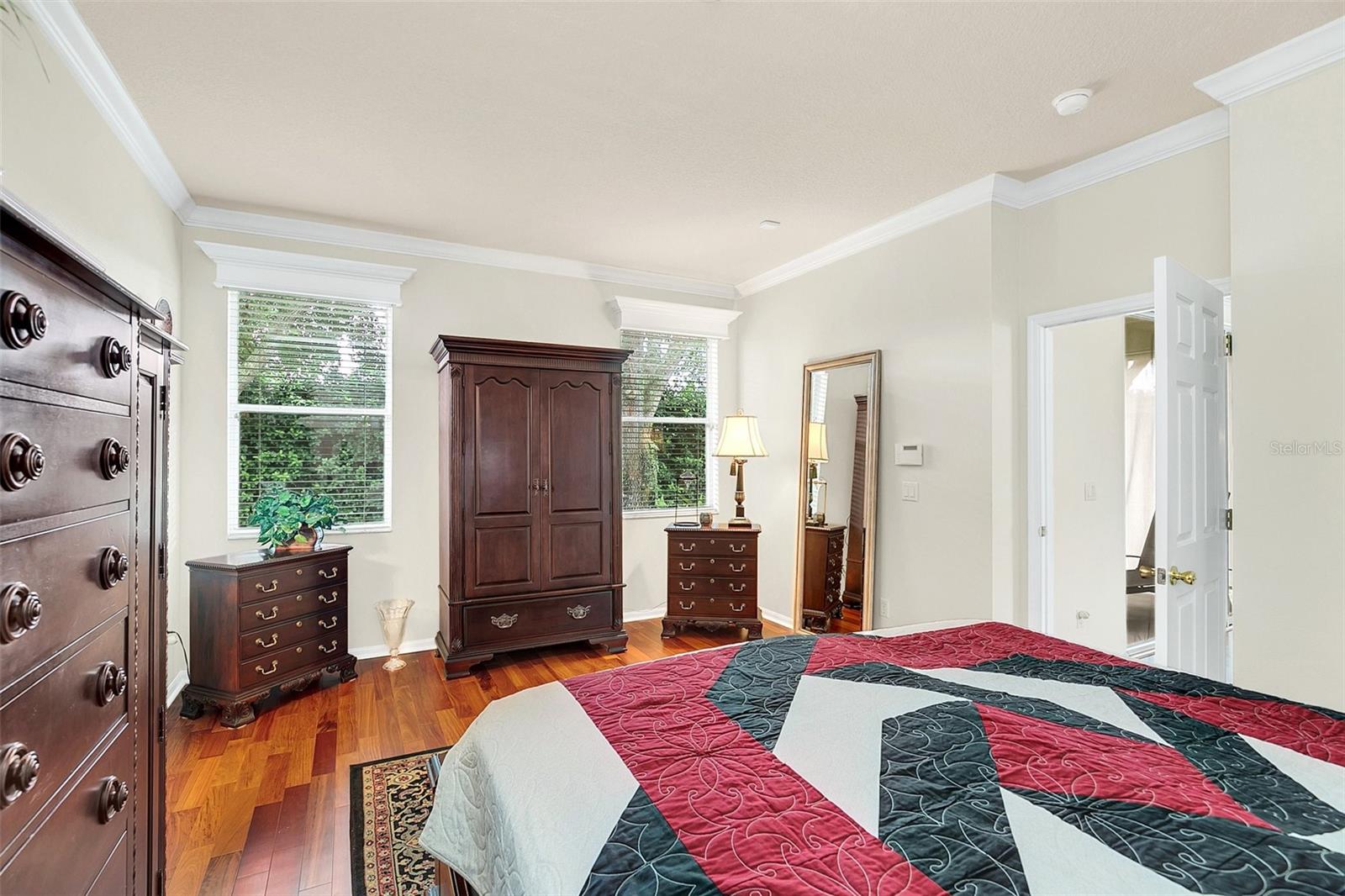 Bedroom with a bold red, black, and white quilt and dark wood furniture.