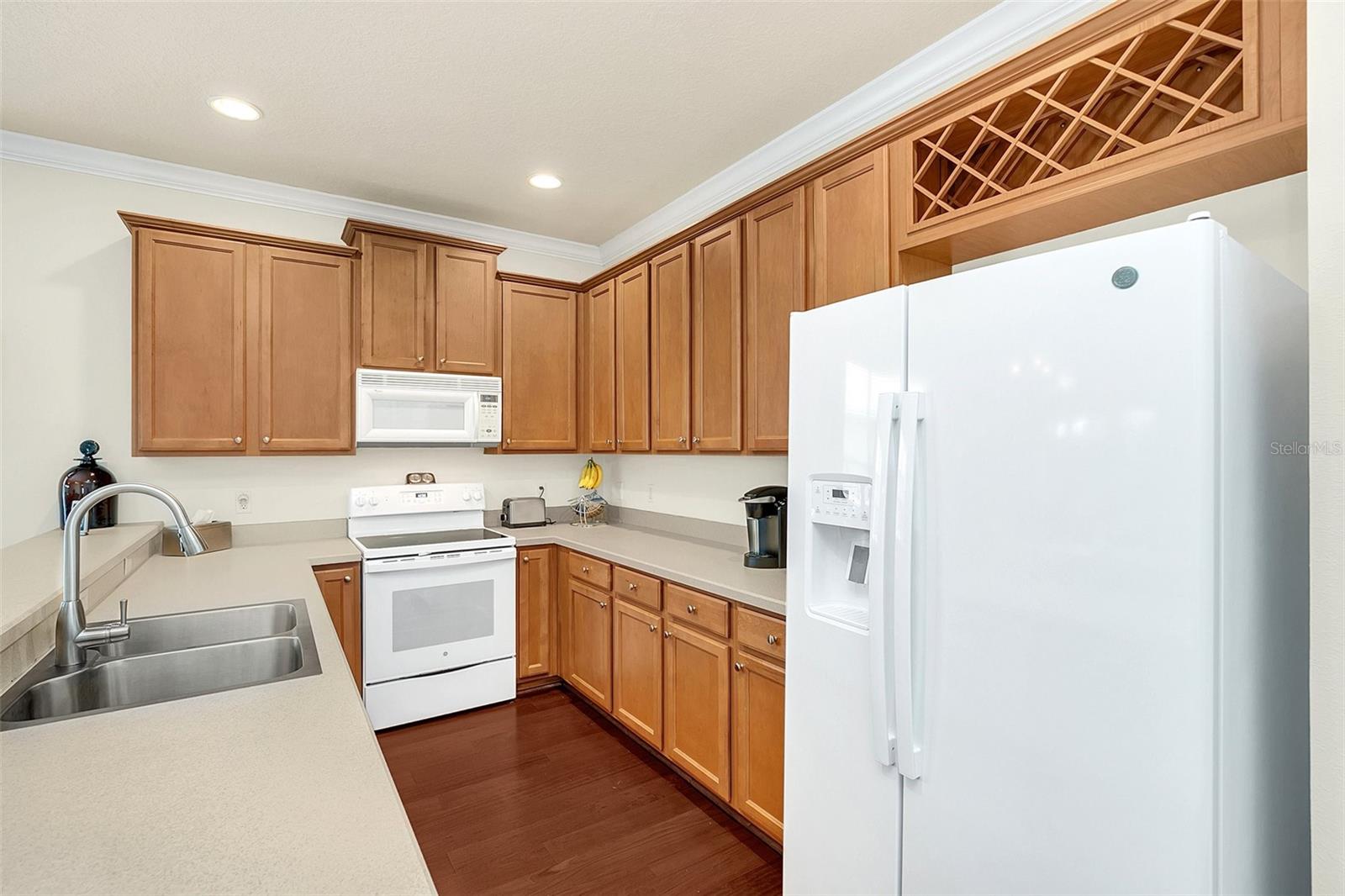 Kitchen with warm wood cabinets, white appliances, and a built-in wine rack.