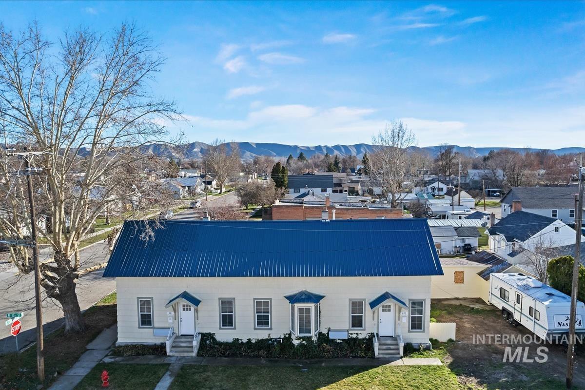 White building with a blue metal roof at a street corner, with mountains in the distance.