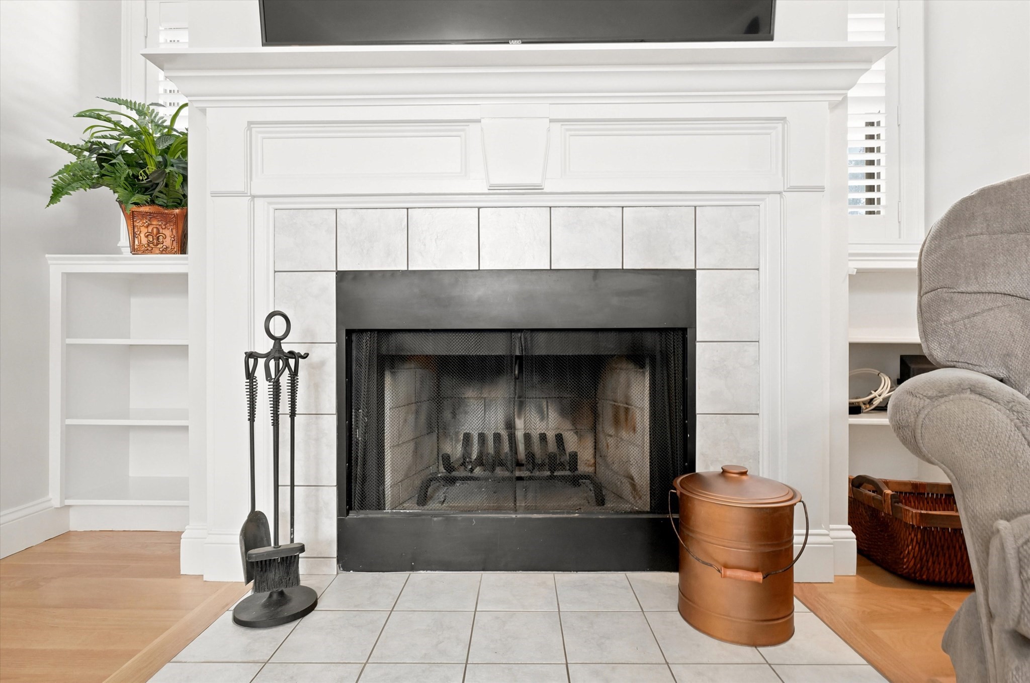 Living room fireplace with a white paneled mantel, tiled surround, and black mesh screen.