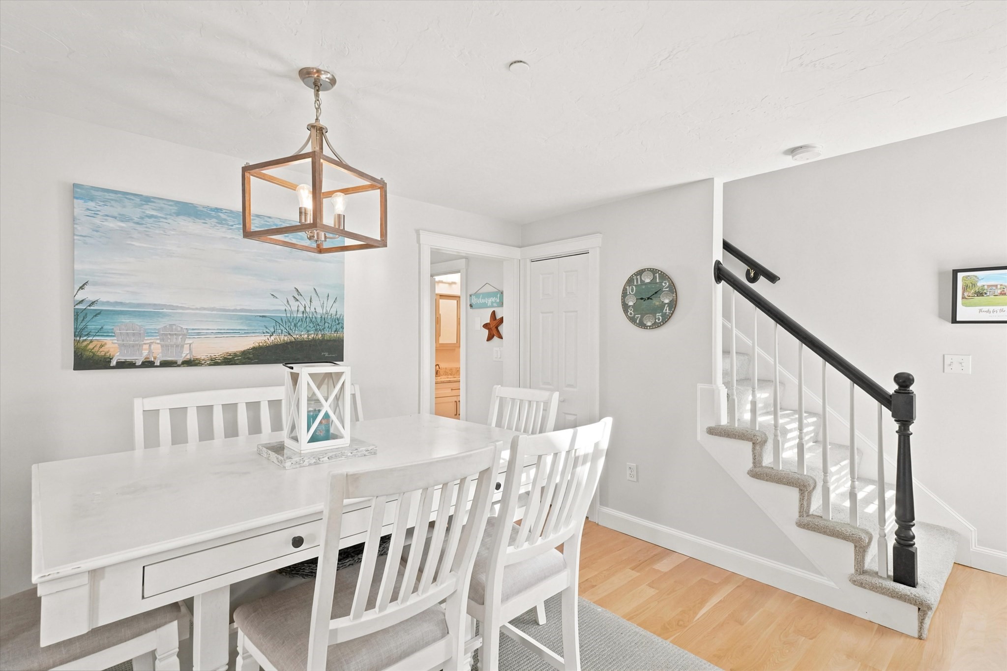 Dining room with white table and chairs beside a carpeted staircase with dark railing.
