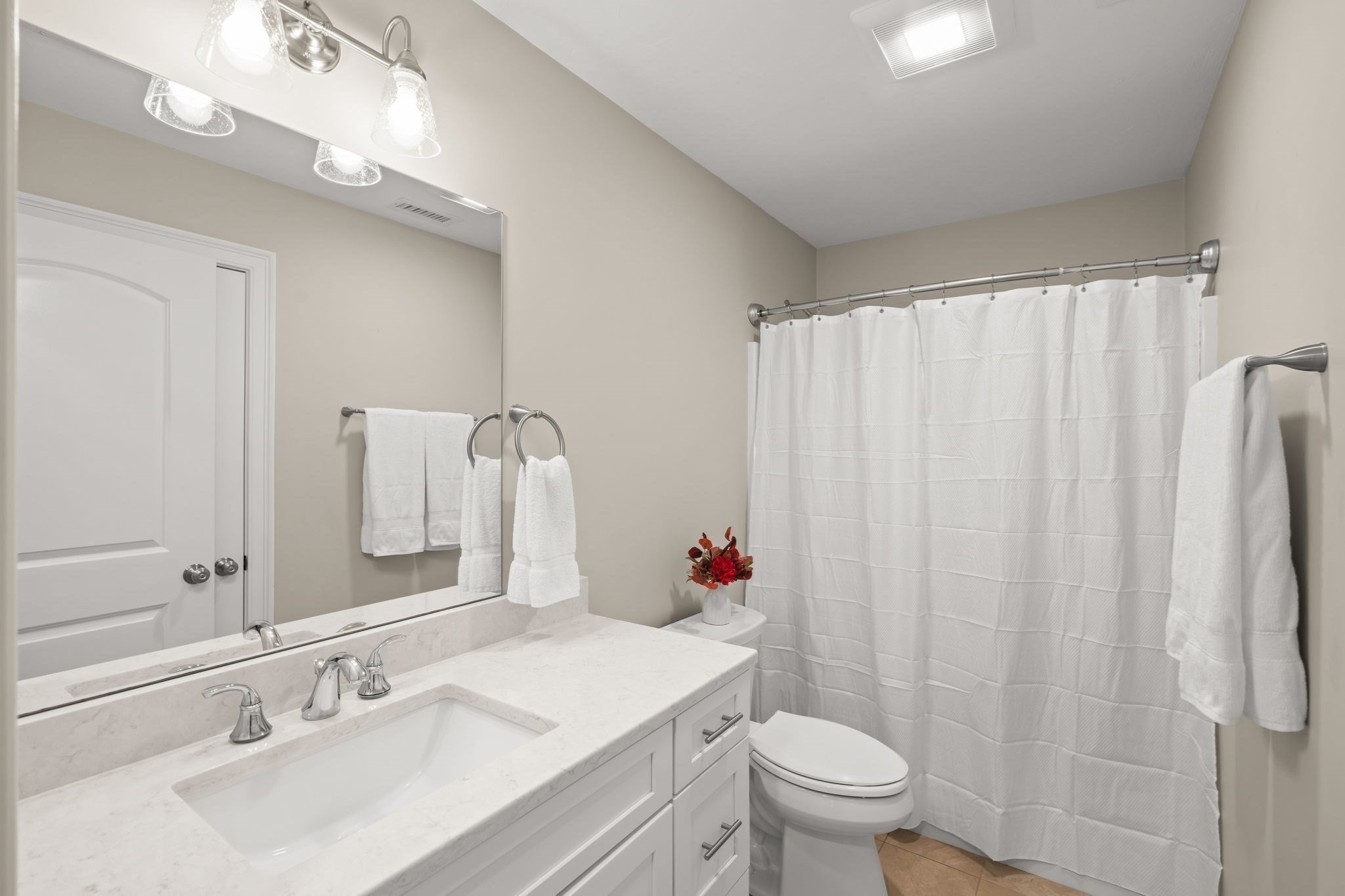 Bathroom with a white vanity, large mirror, and shower curtain.