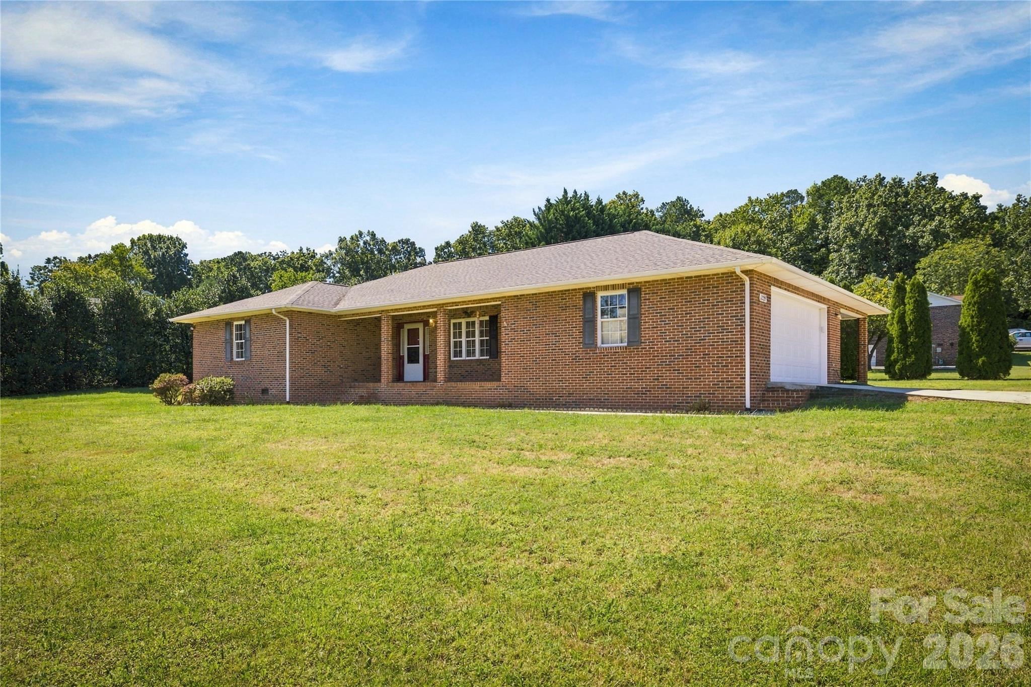 Single-story brick house with an attached garage and broad lawn.