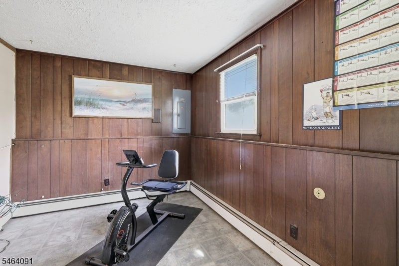 Exercise room with a stationary bike and bench, wood-paneled walls, and a window.