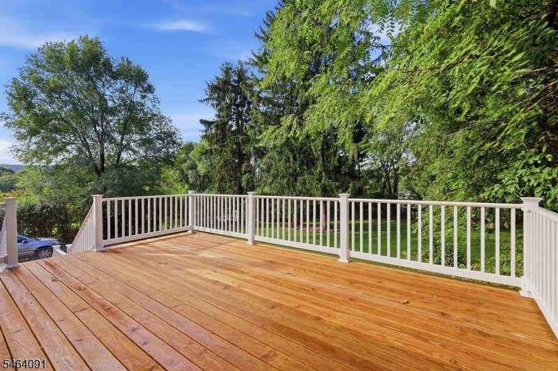 Wood-plank deck with white railings overlooking a leafy yard.