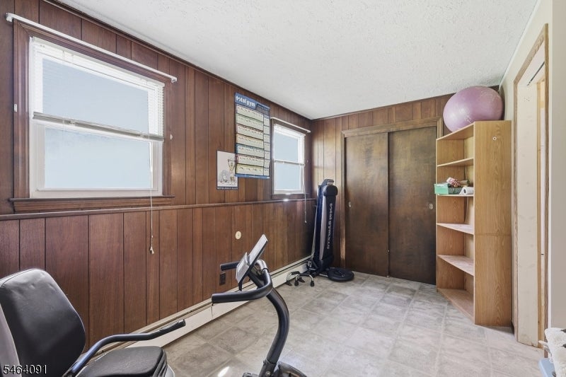 Home exercise room with a stationary bike, treadmill, and dark wood-paneled walls.