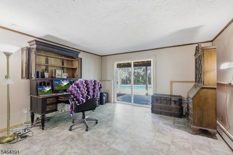 Home office with wooden cabinets, a computer desk, tiled floors, and sliding doors overlooking a pool.