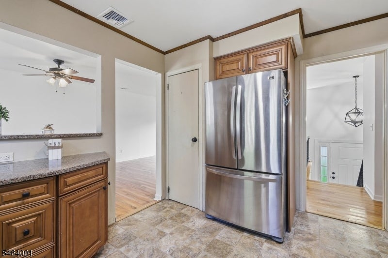 Kitchen with wood cabinetry, granite counters, and a stainless steel refrigerator.