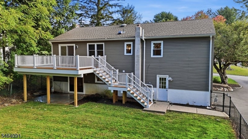 Rear of a gray two-story house with an elevated white-railed deck and staircase.