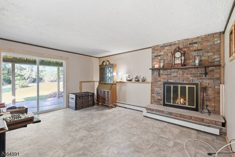 Living room with a brick fireplace, sliding glass doors, and light tile flooring.
