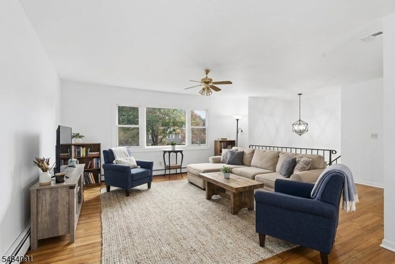 Living room with a beige sectional, navy armchairs, hardwood floors, and three large windows.
