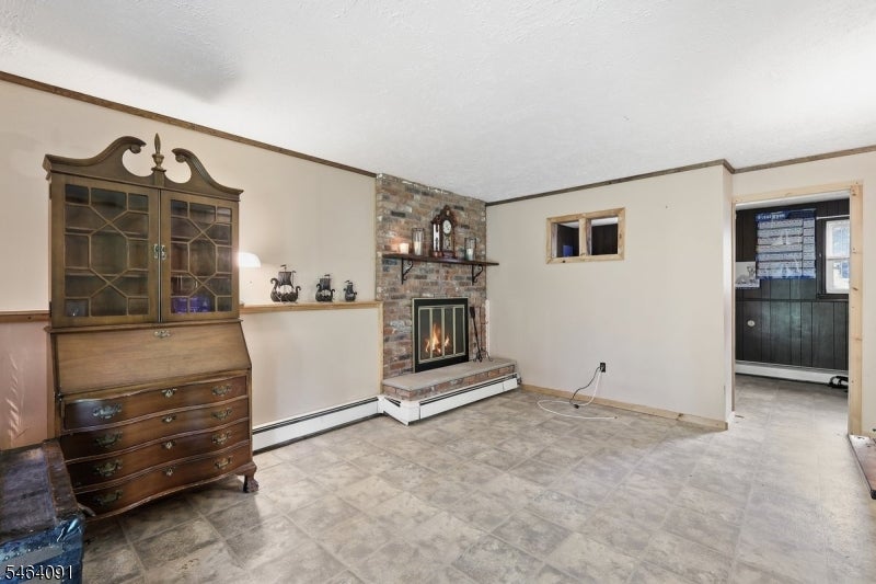Living room with a brick fireplace, tiled floor, and dark wooden china cabinet.