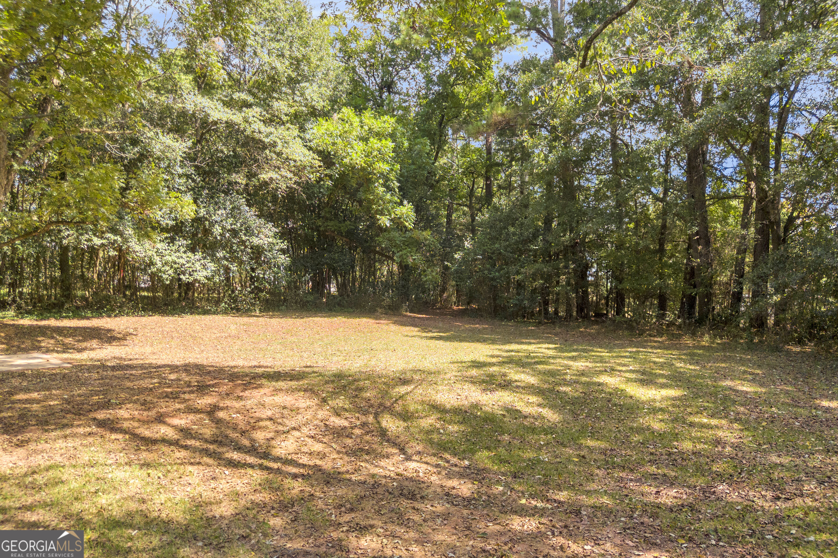 Wooded property with a broad grassy clearing and mature trees.