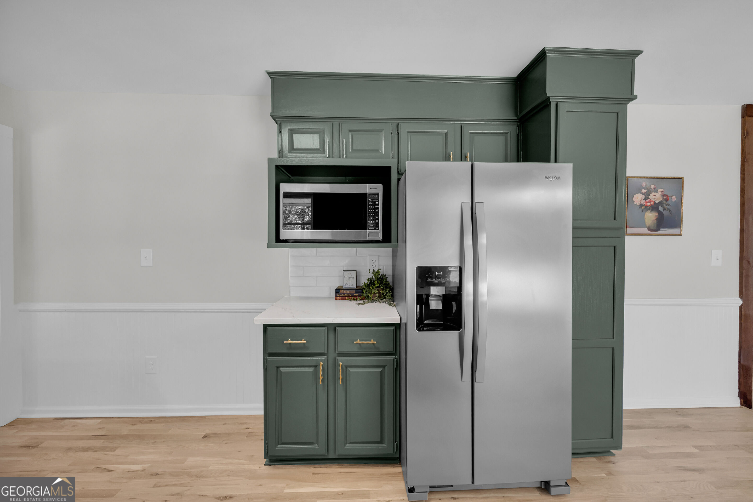 Kitchen with dark green cabinetry, brass hardware, and a stainless steel side-by-side refrigerator.