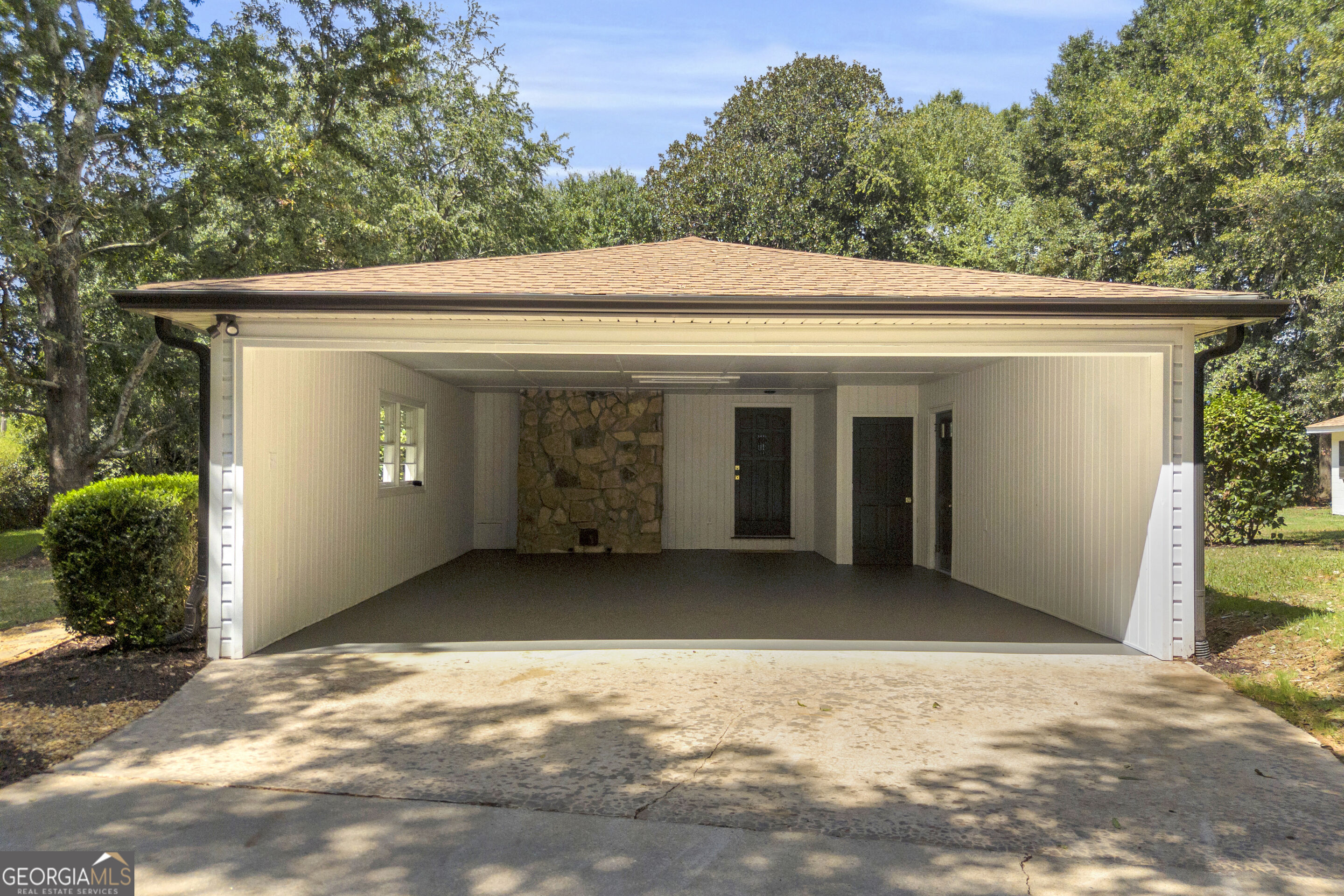 House with a wide open garage and stone accent wall.