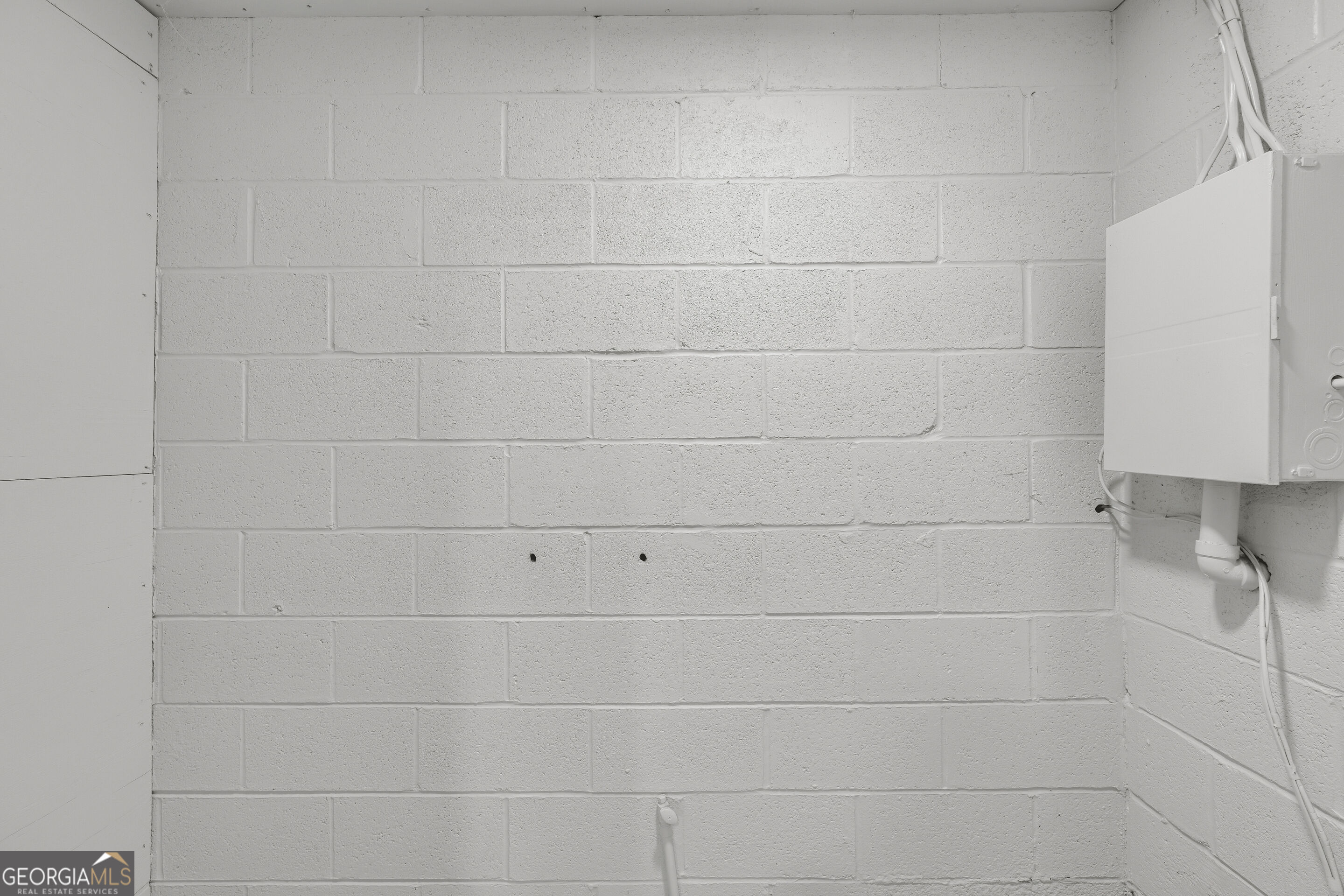 Cinder block utility wall with an electrical panel and exposed wiring.