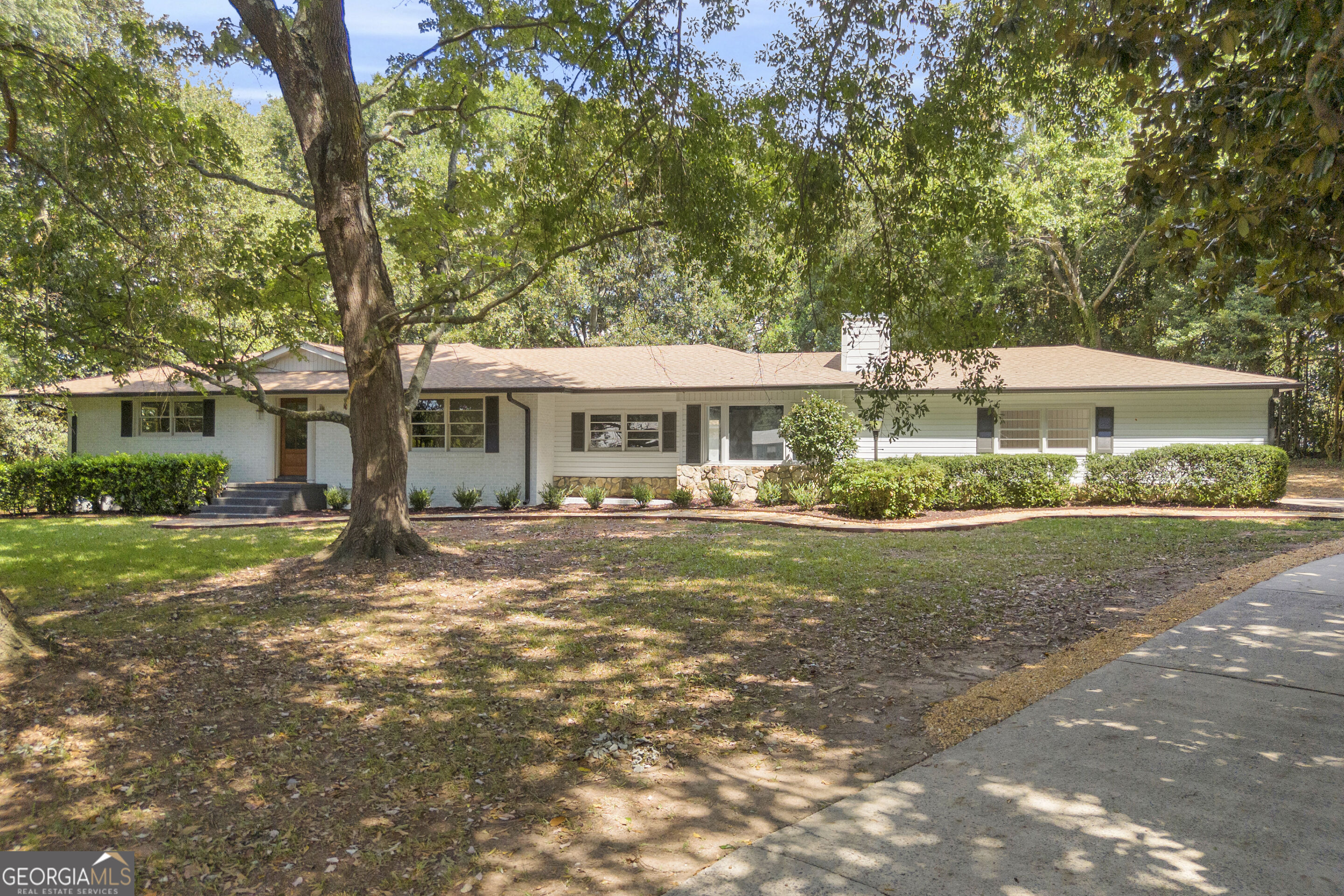 Single-story ranch house with a stone accent, shaded by a large front-yard tree.