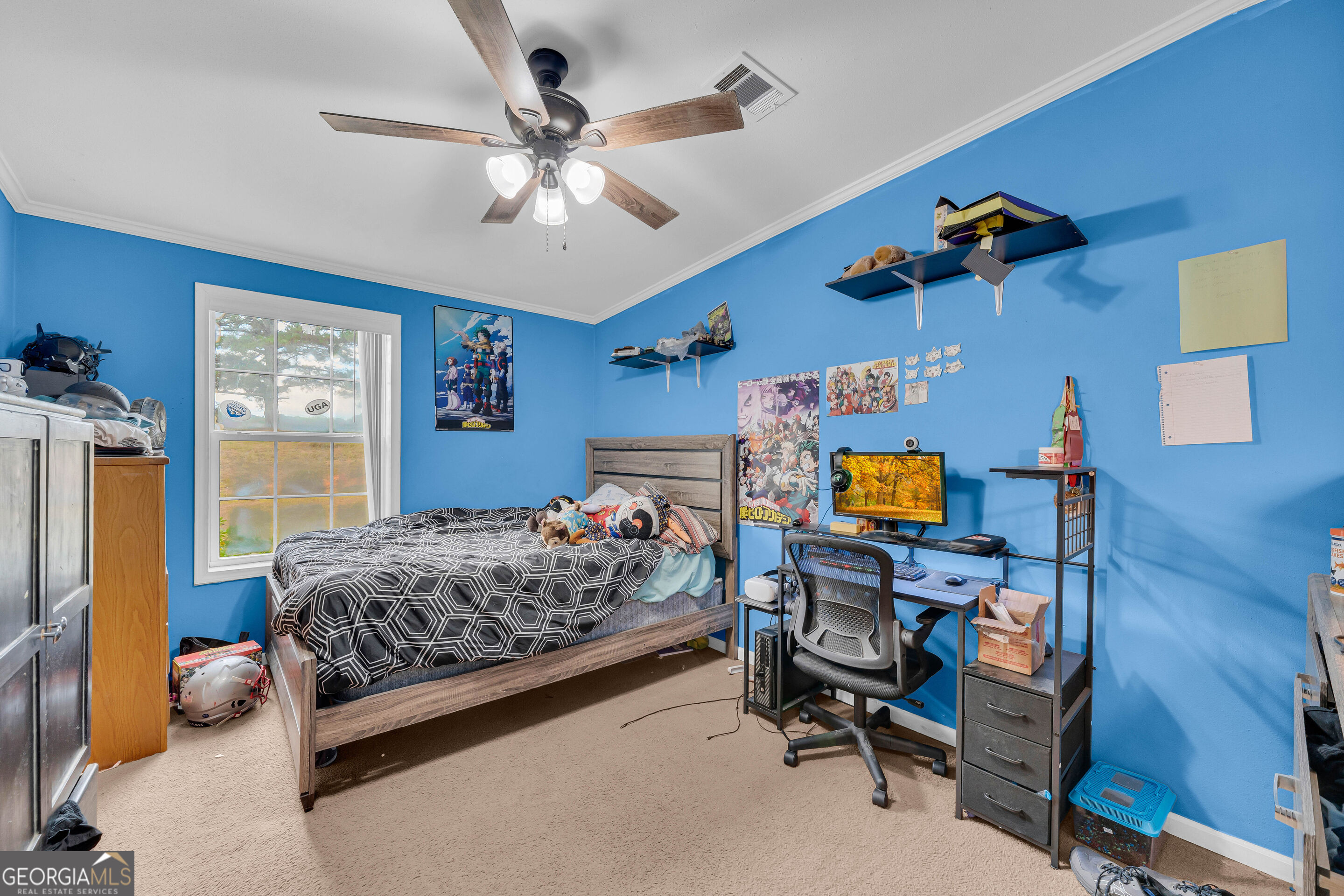 Blue bedroom with a wood-framed bed and a computer desk beside the window.