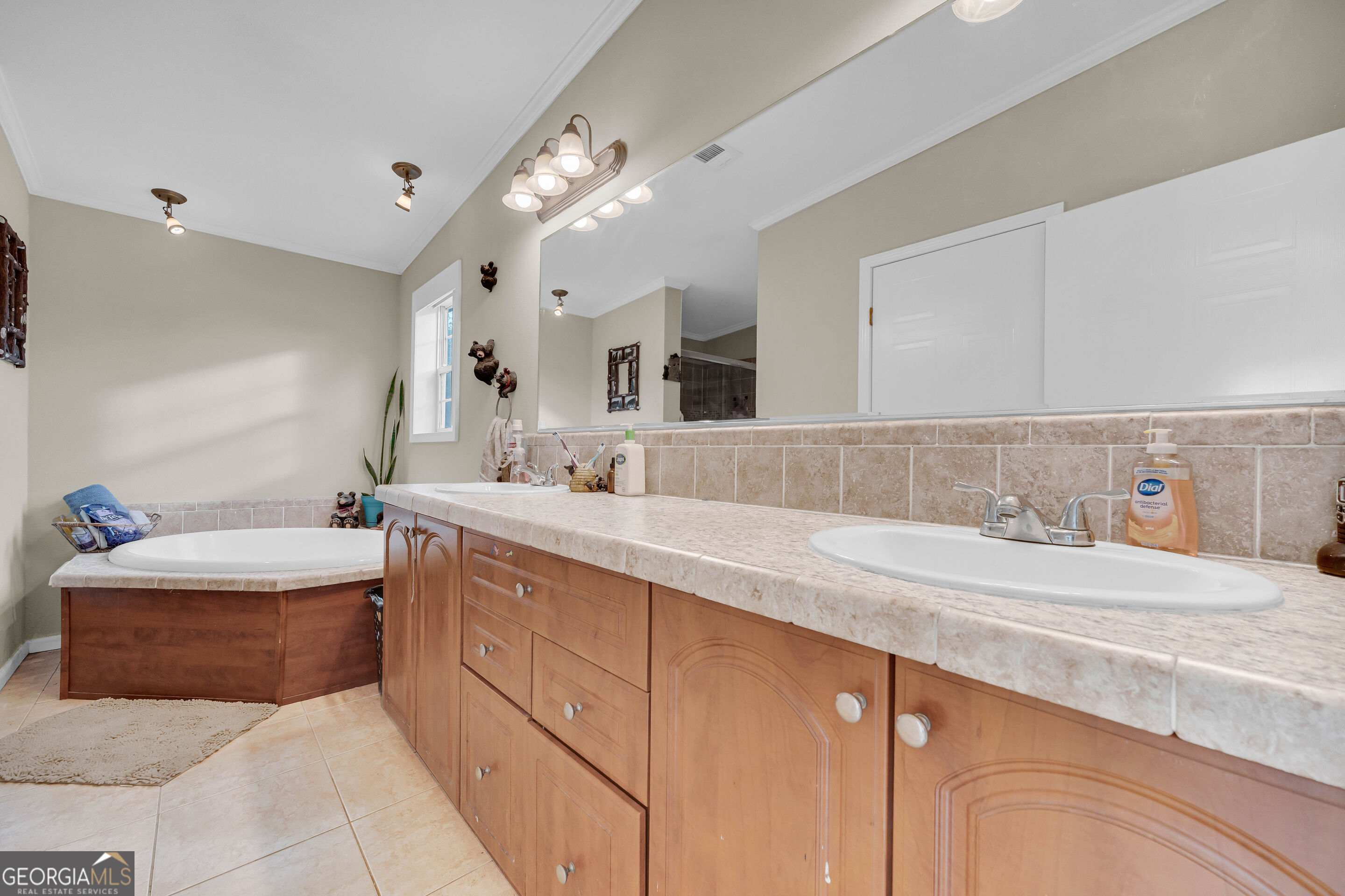 Bathroom with a long double-sink wood vanity and a built-in soaking tub.