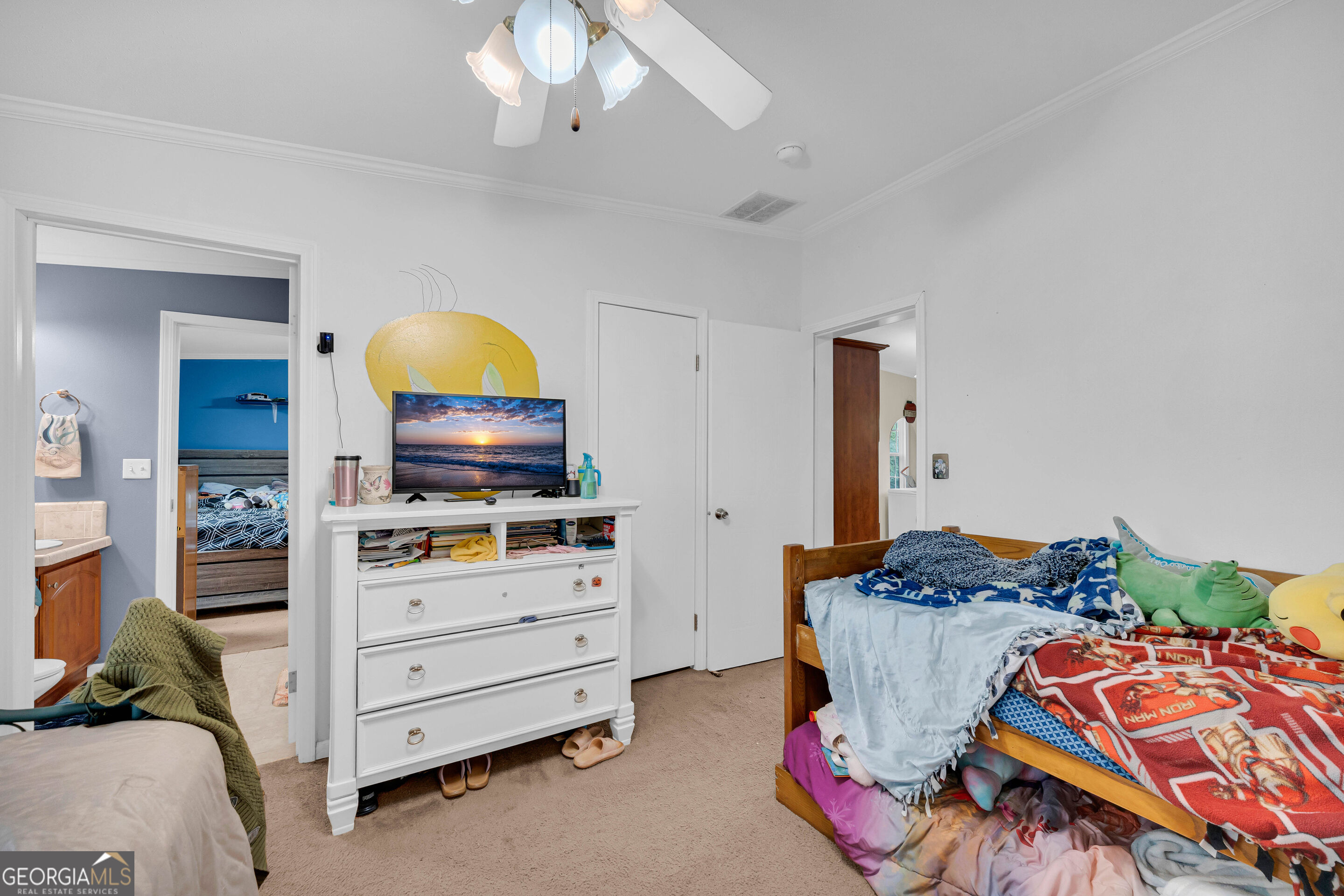 Bedroom with two beds, a white dresser and television, and an Iron Man blanket.