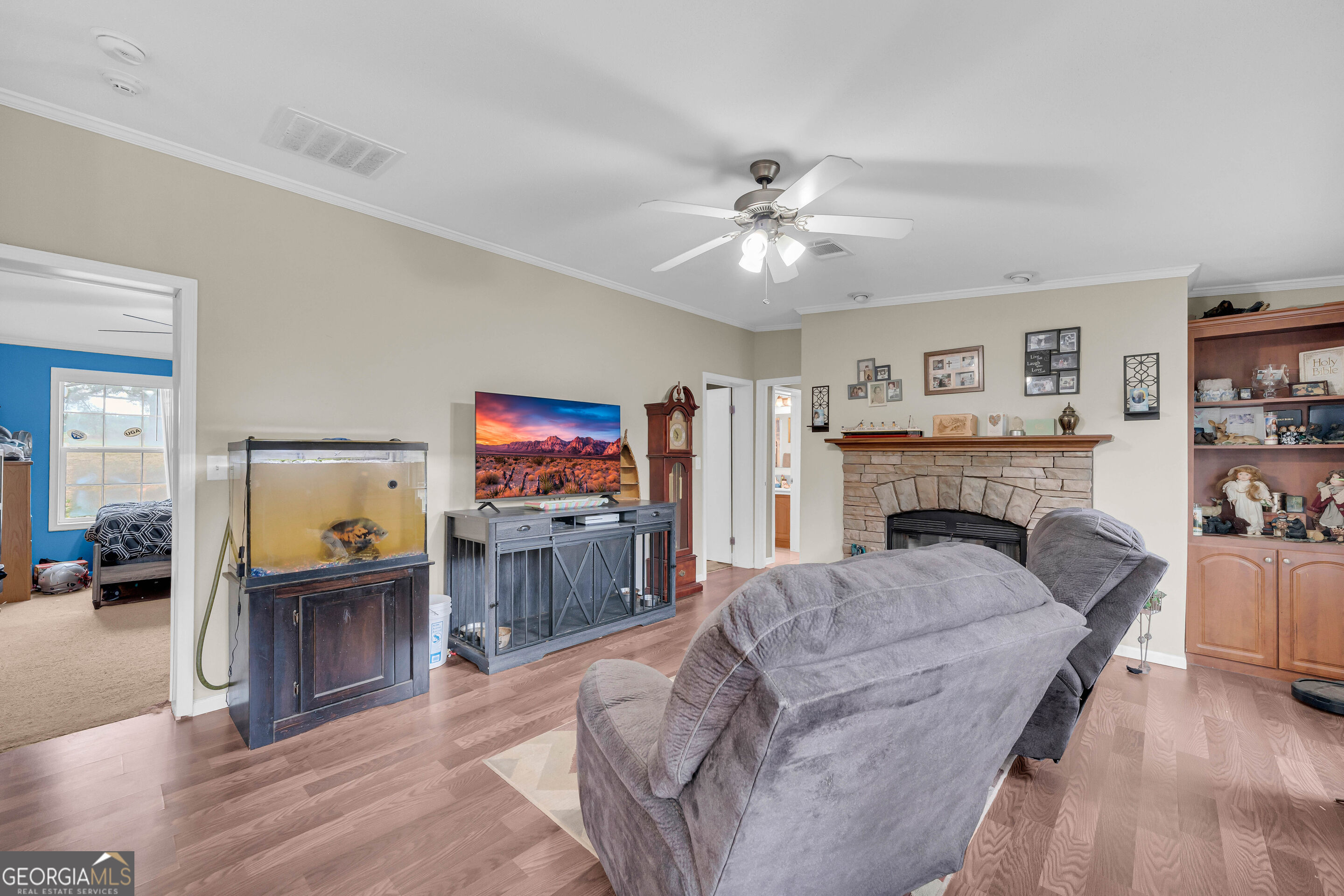 Furnished living room with a stone fireplace, gray sofa, and large aquarium.