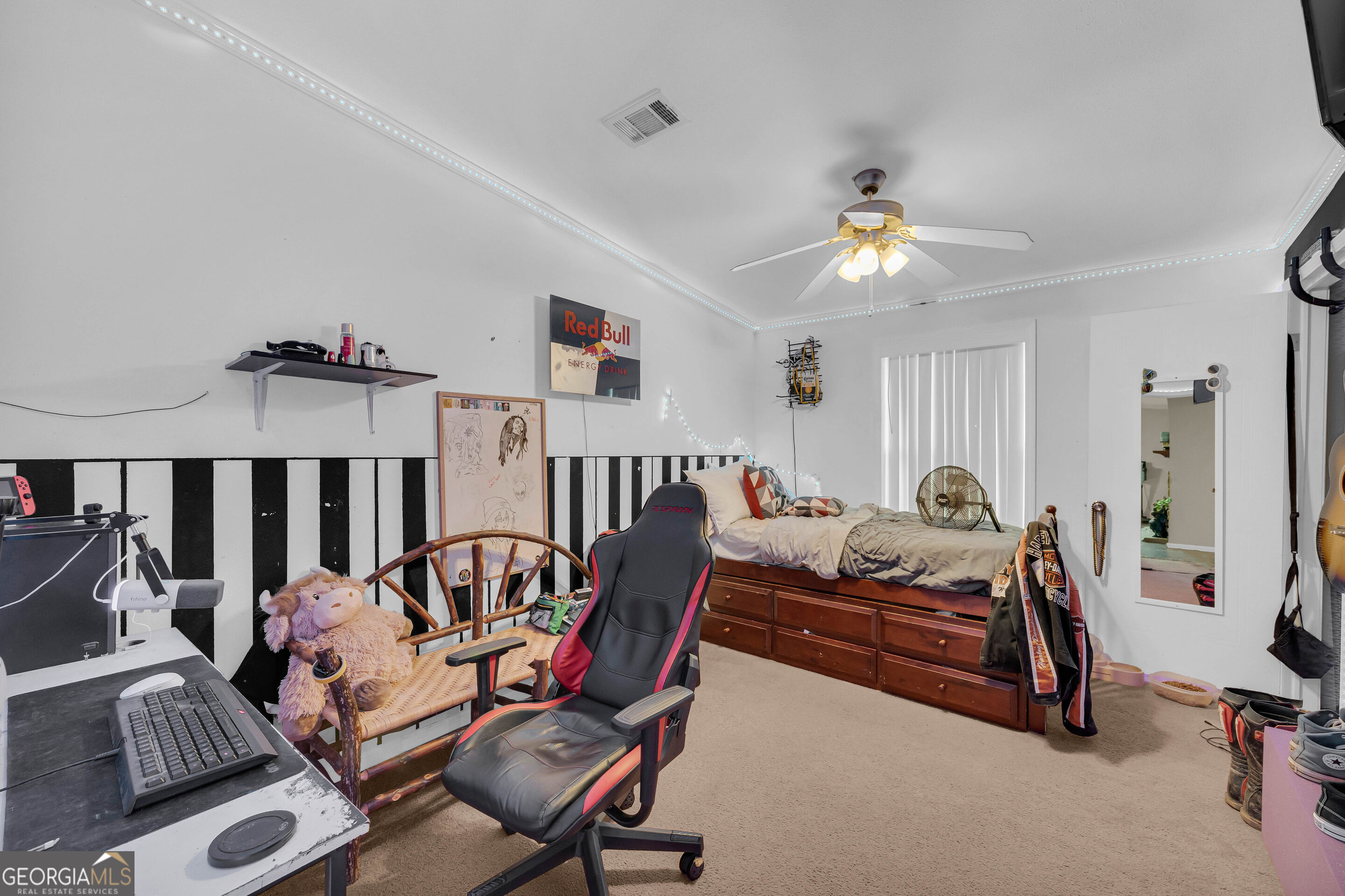 Bedroom with a gaming setup, wooden storage bed, and blue LED ceiling lights.