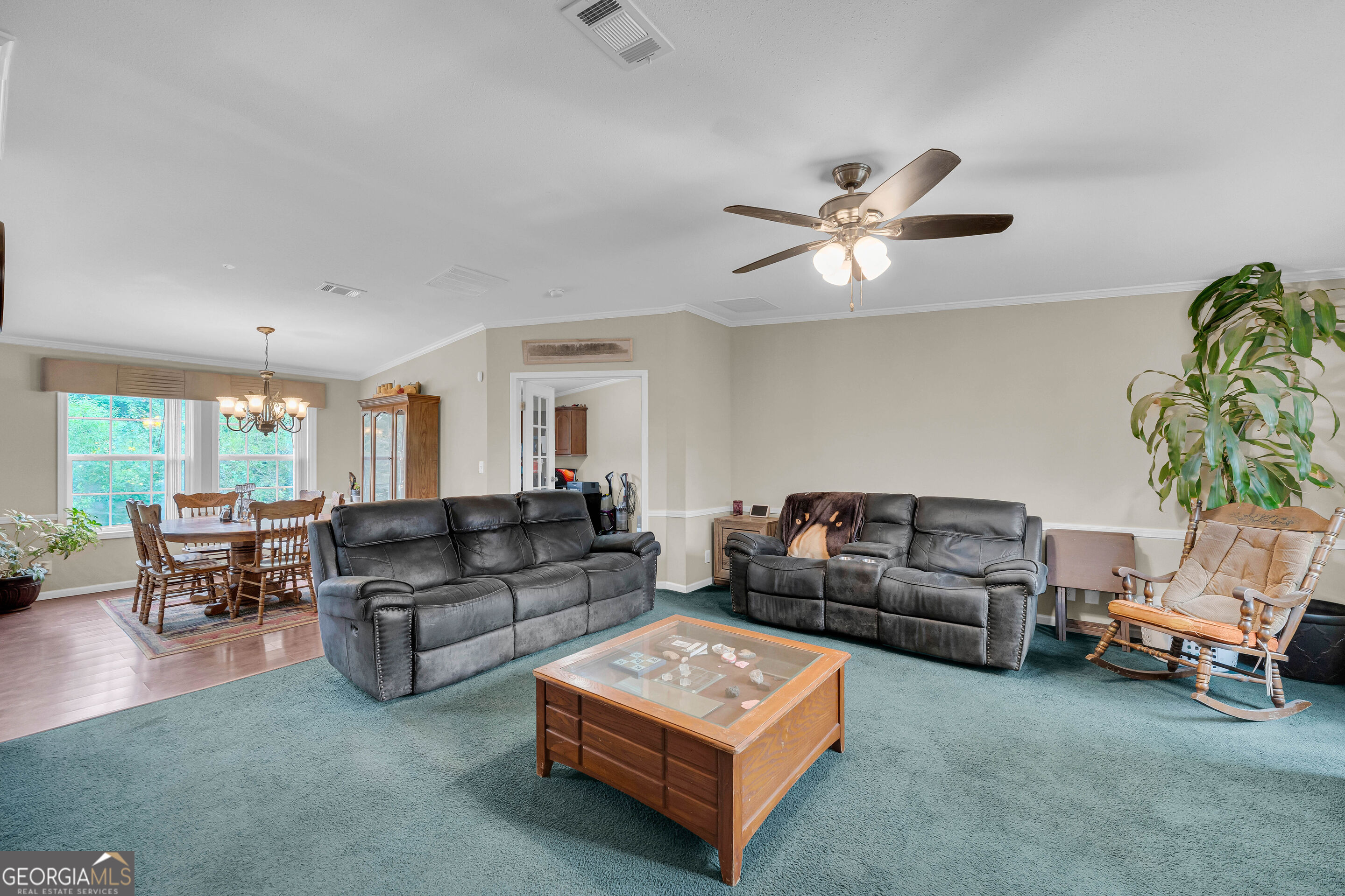 Living room with gray leather sofas, teal carpet, and an adjoining dining area.