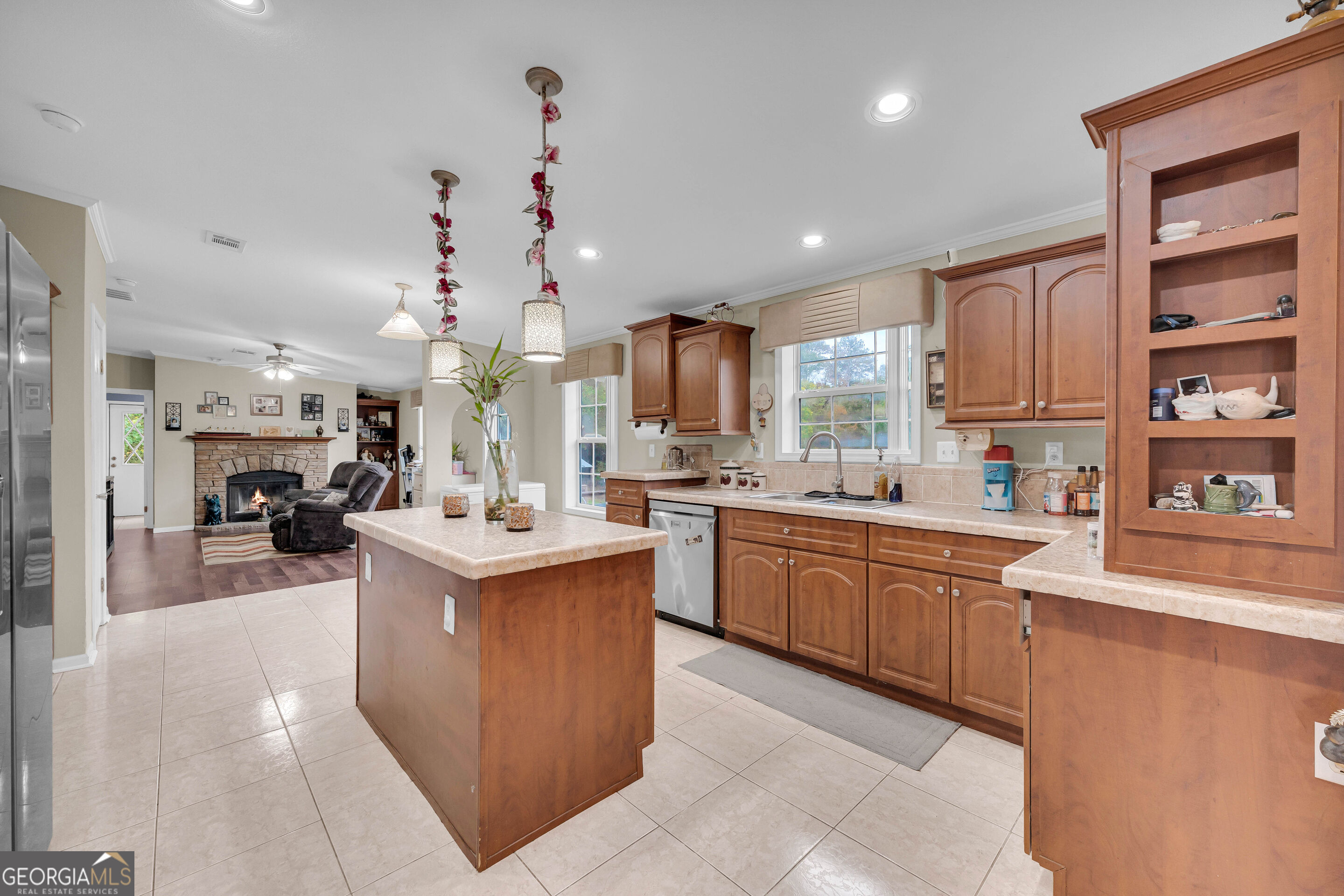 Kitchen with a wood island and cabinetry opening onto a living room with a stone fireplace.