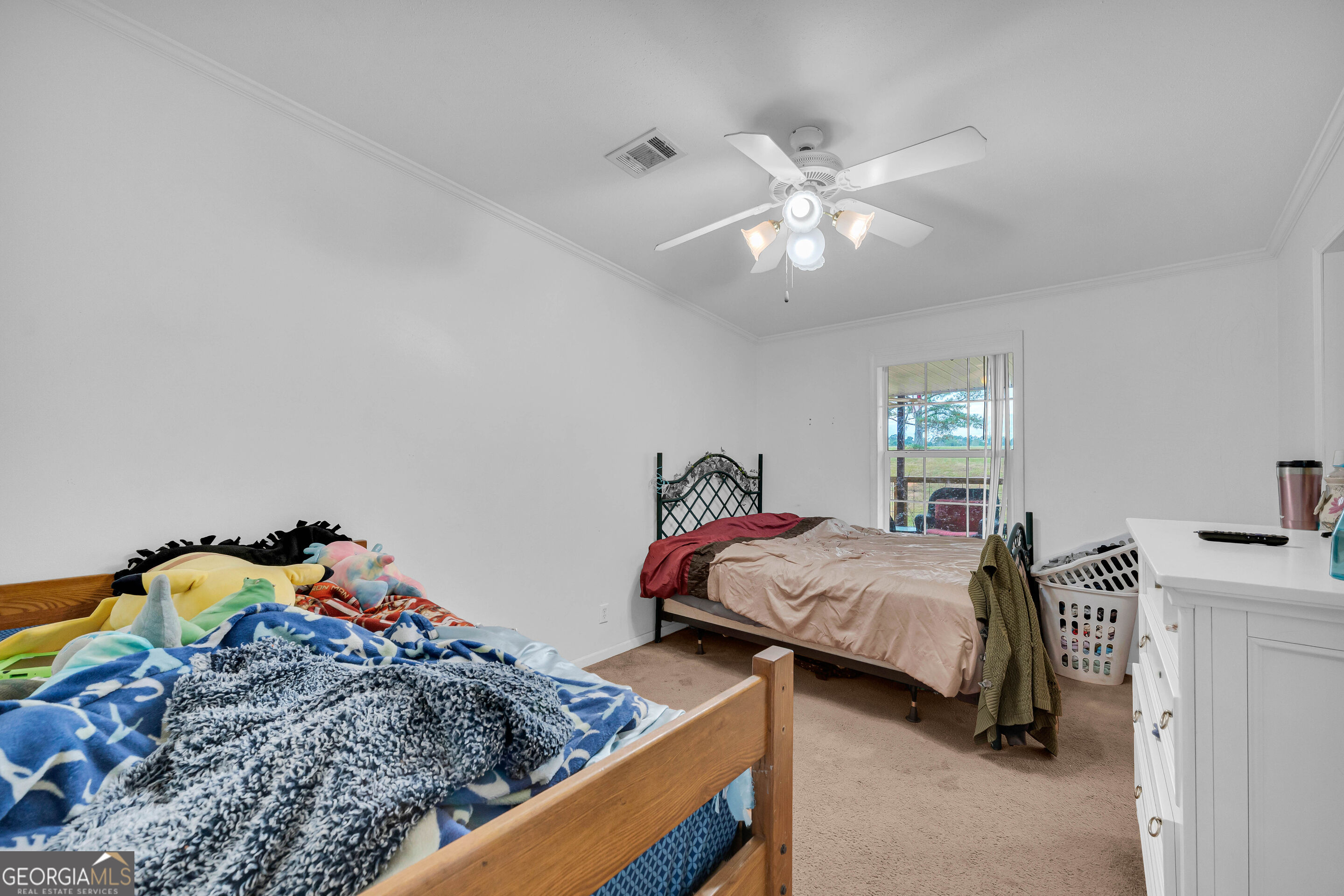 Bedroom with two beds, a ceiling fan, and a window overlooking the yard.