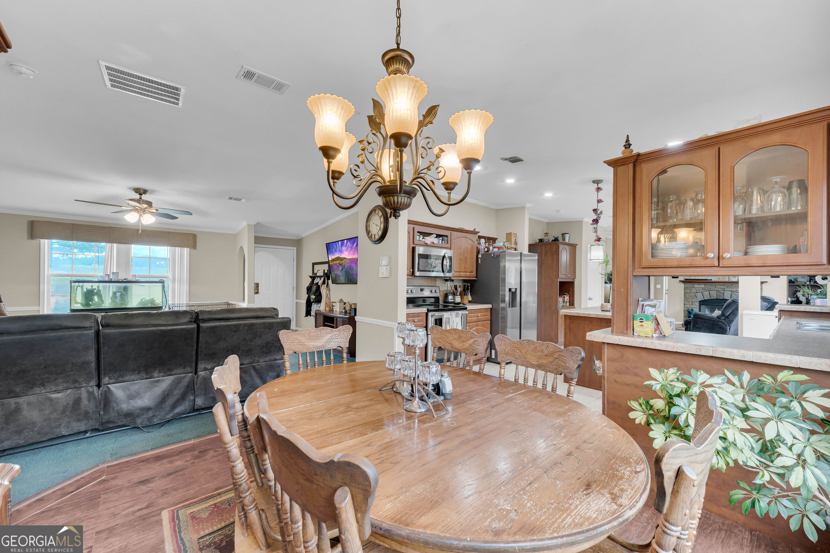 Dining area with a large oval wooden table and chandelier beside the kitchen and living room.