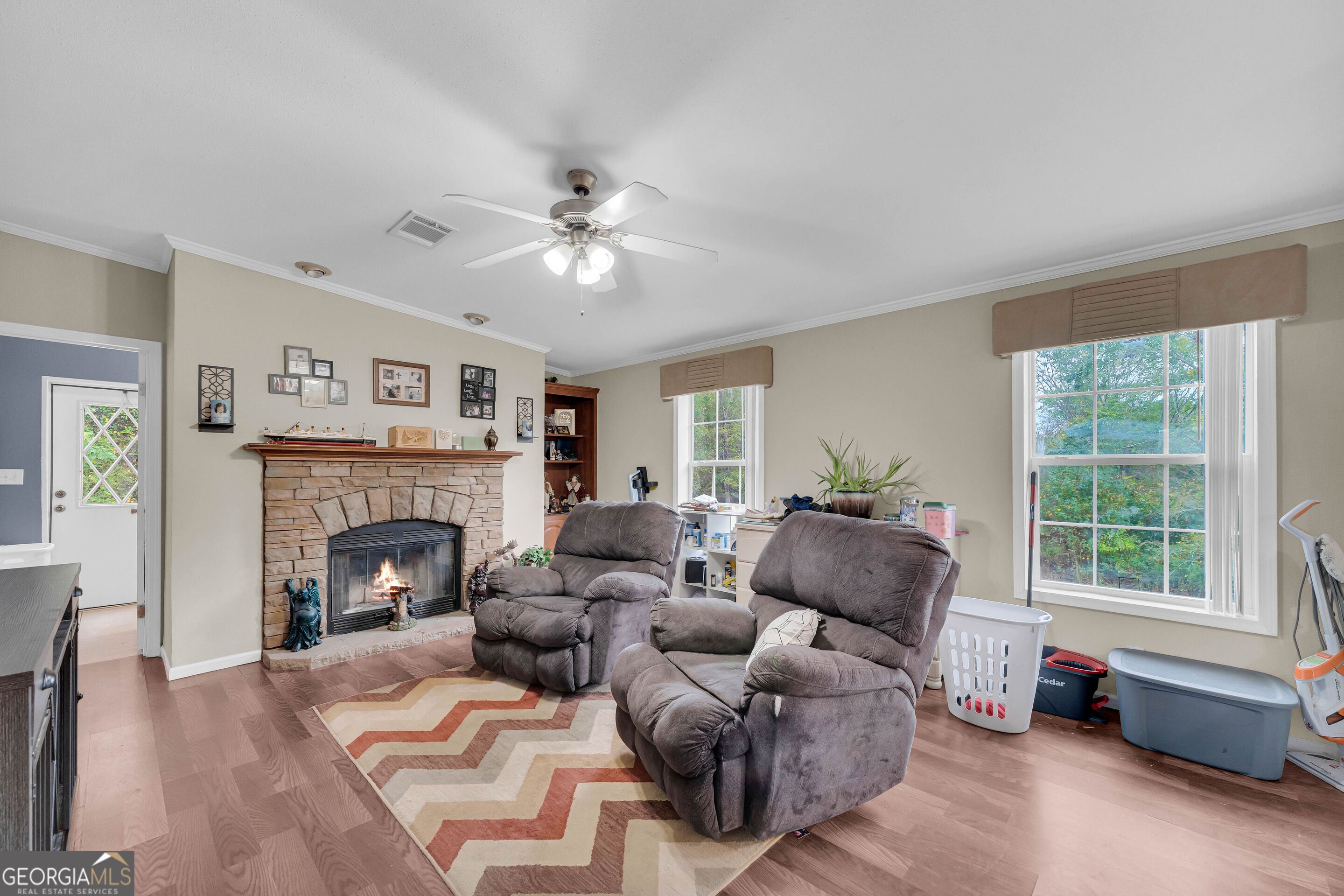 Living room with a stone fireplace, two recliners, and large windows.