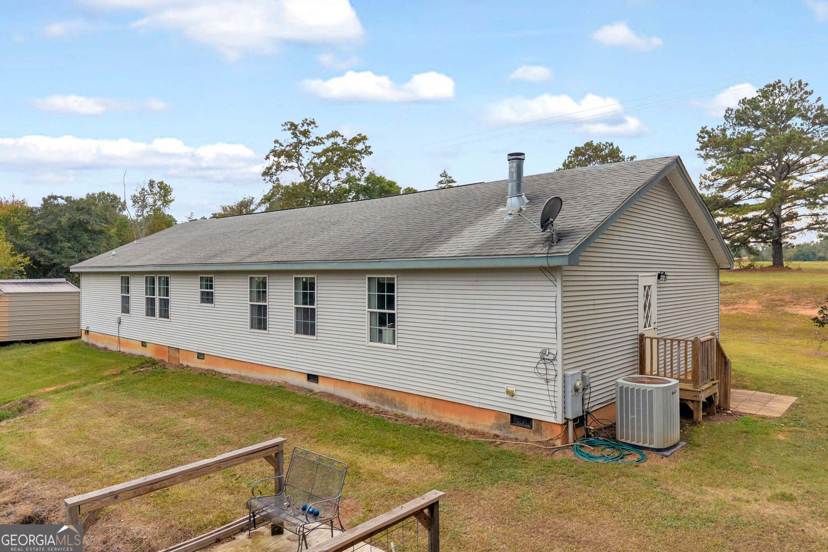 Rear side of a single-story home with a small deck and grassy yard.