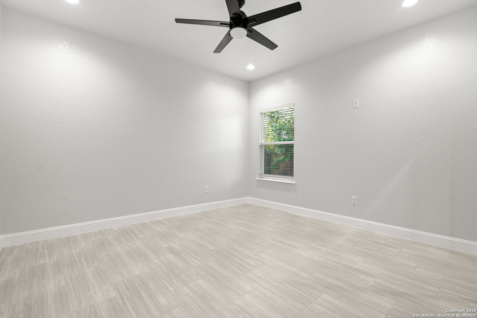 Empty room with light tile flooring, a ceiling fan, and a window with blinds.