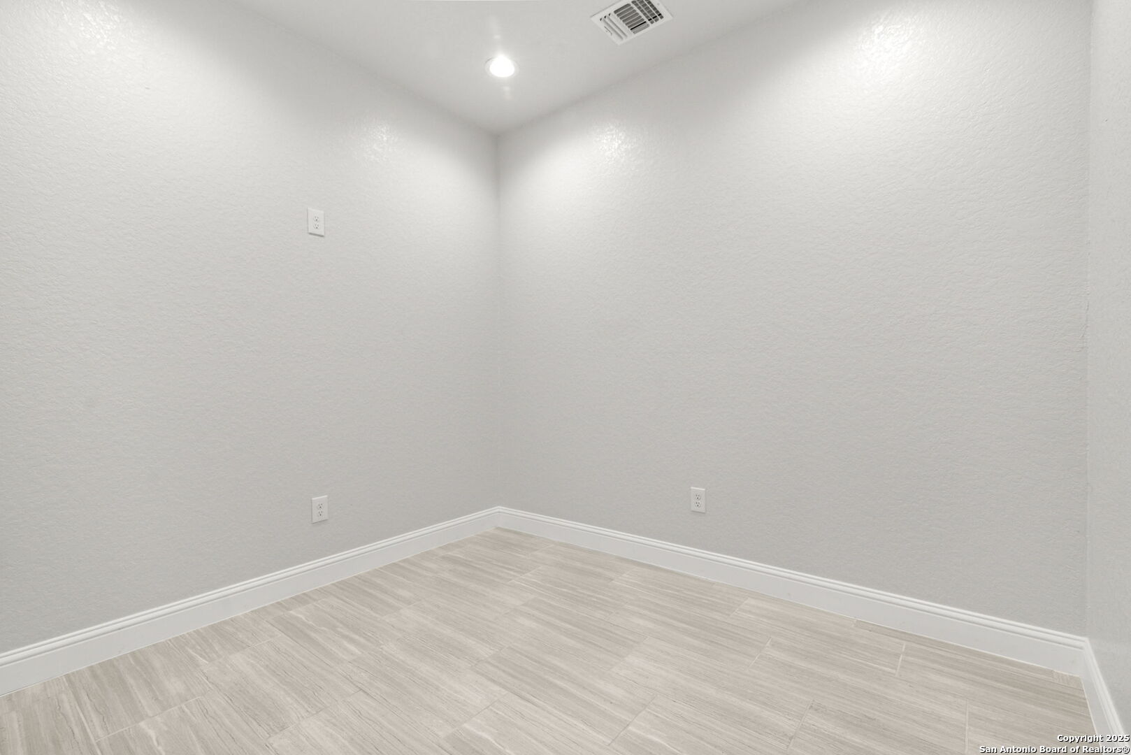 Empty room with light tile flooring, white walls, and a recessed ceiling light.