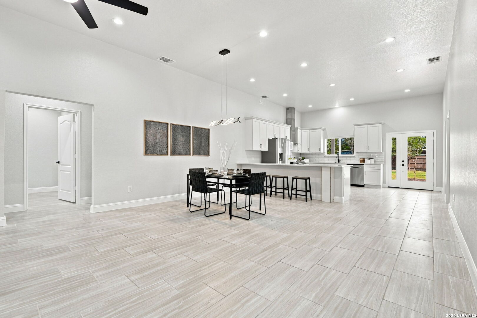 Open kitchen and dining area with white cabinetry, a large island, and tiled floors.
