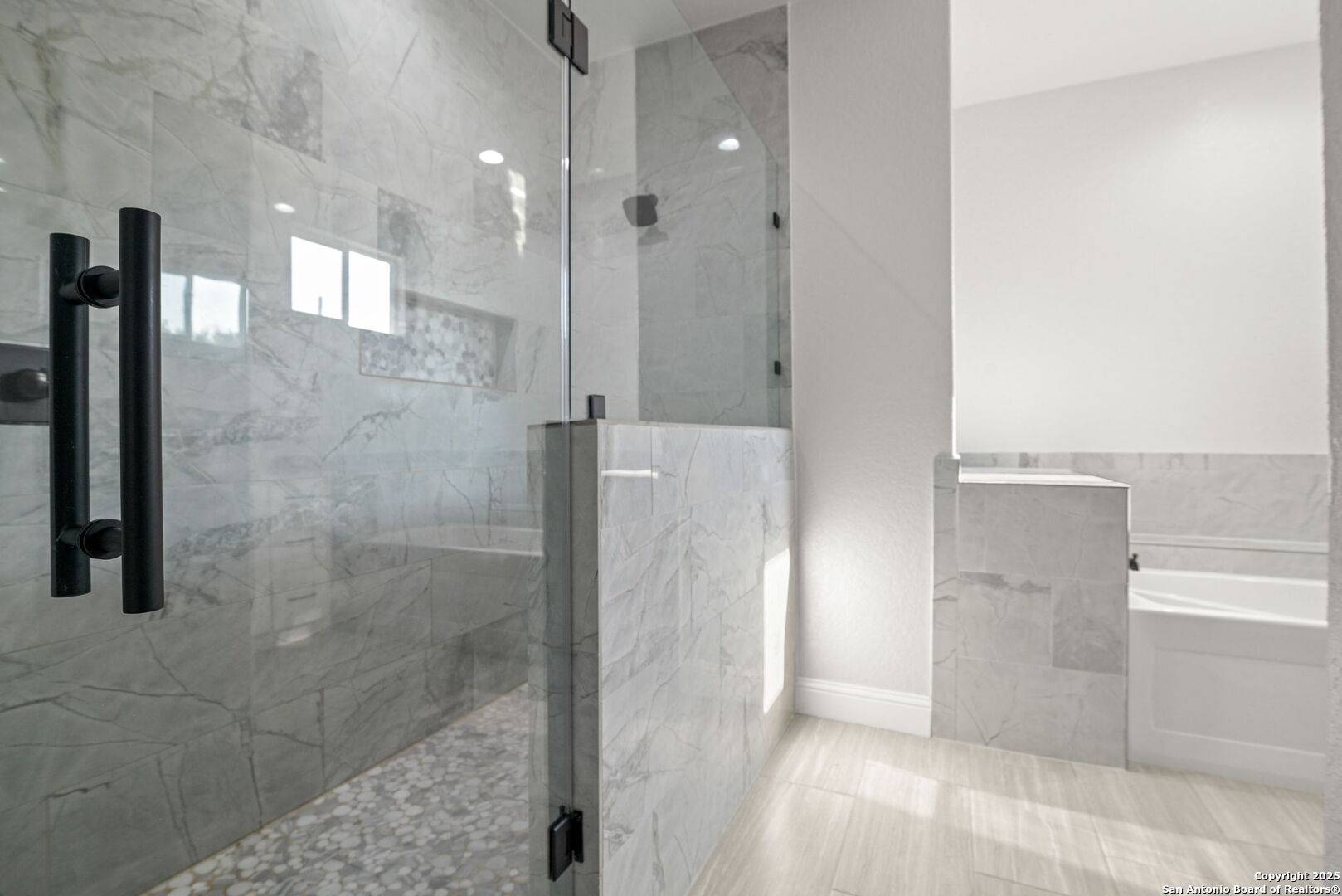 Marble-tiled bathroom with a glass-enclosed shower and bathtub.