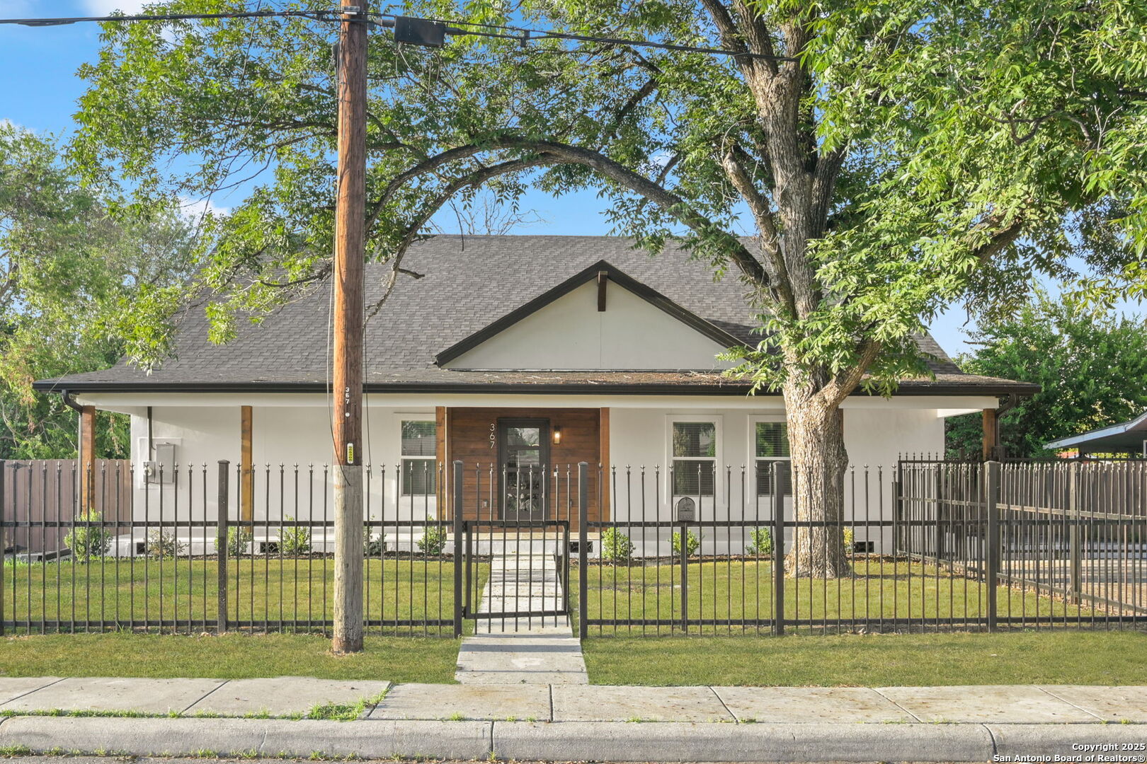 367 Rosebud single-story home with a wood-accented entry, mature shade tree, and fenced front yard.