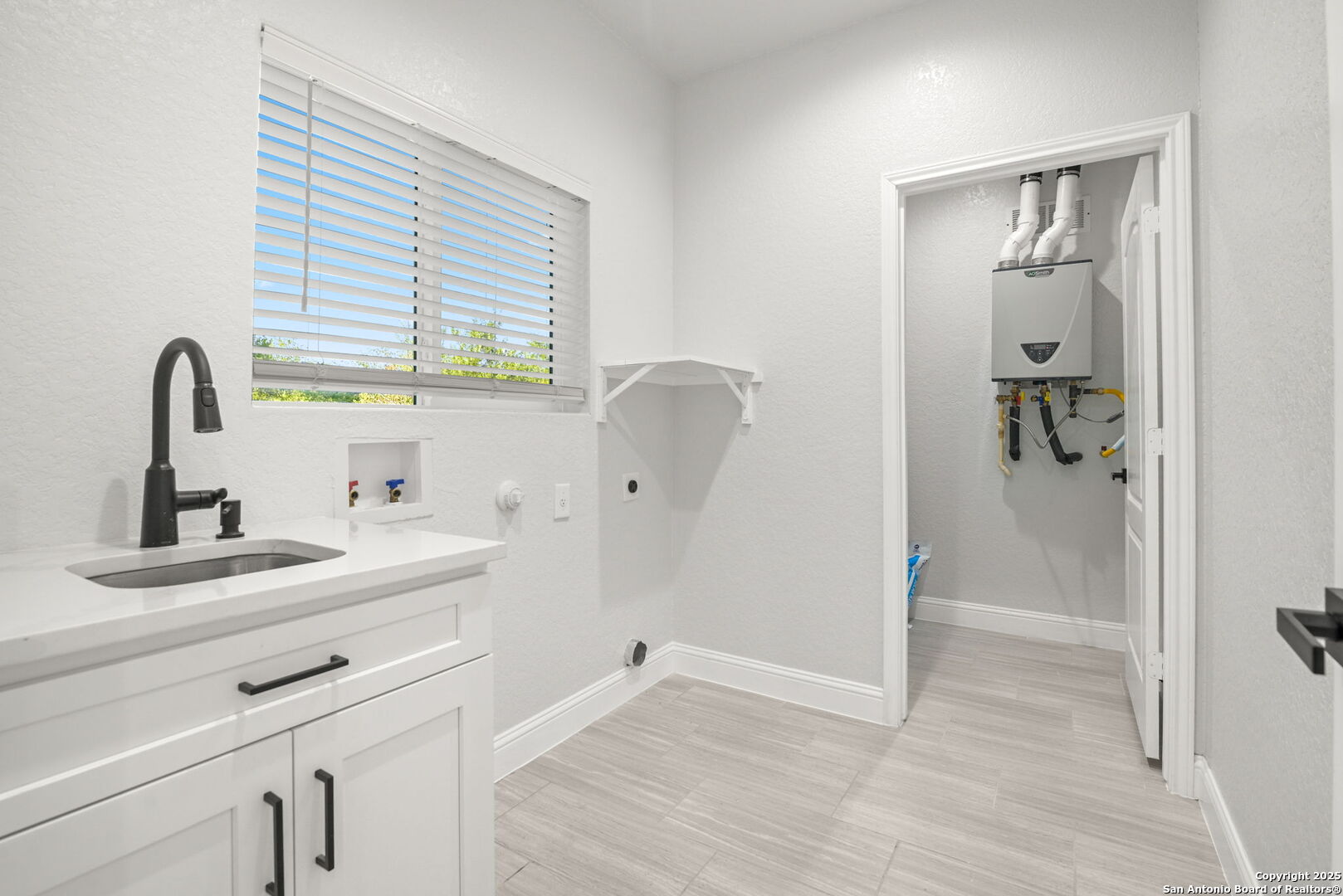 Laundry room with a utility sink, washer hookups, and a tankless water heater.