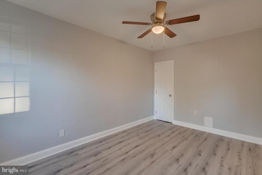 Vacant room with gray walls, wood-look flooring, a window, and a ceiling fan.