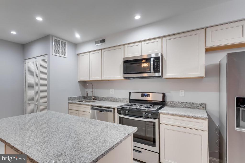 Kitchen with white cabinets, granite counters, stainless steel appliances, and a gas range.