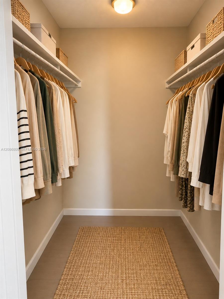 Walk-in closet with clothes on both sides, woven storage baskets, and a natural-fiber rug.