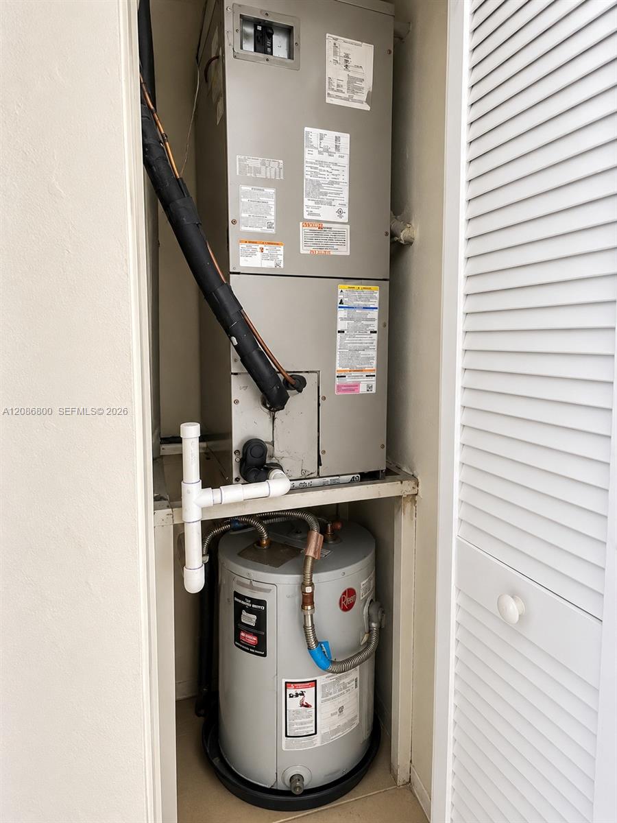 Utility closet with an air handler above a tank-style water heater.