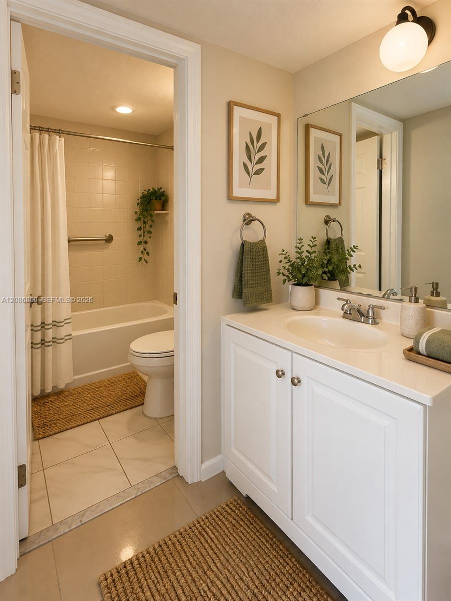 Bathroom with white vanity and large mirror beside a tub and toilet.